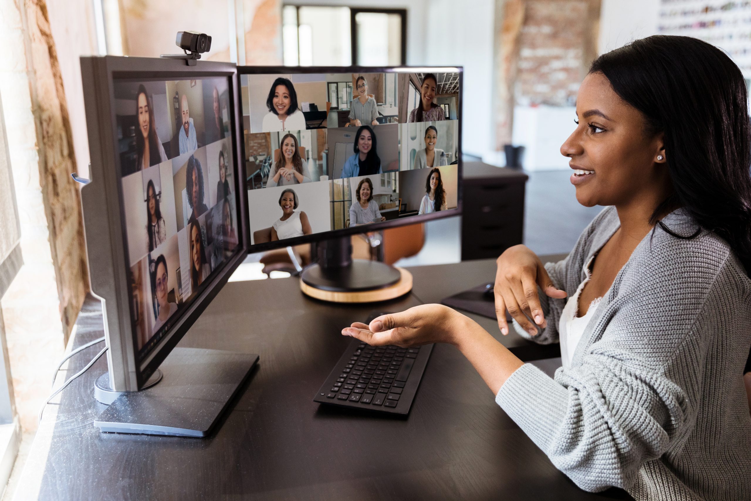 image: a woman with dark skin and dark hair in a virtual with other colleagues on a house setting